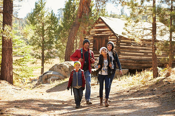 Fotografía de una familia junto a una cabaña de madera en un bosque (imagen de ejemplo)